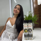 Woman in a white dress sitting next to two bottles of Versada hair care products.